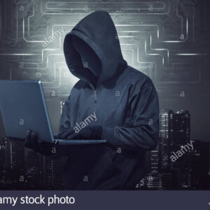 hooded hacker holding laptop while typing R57BJ2 Hackers Crime Informático